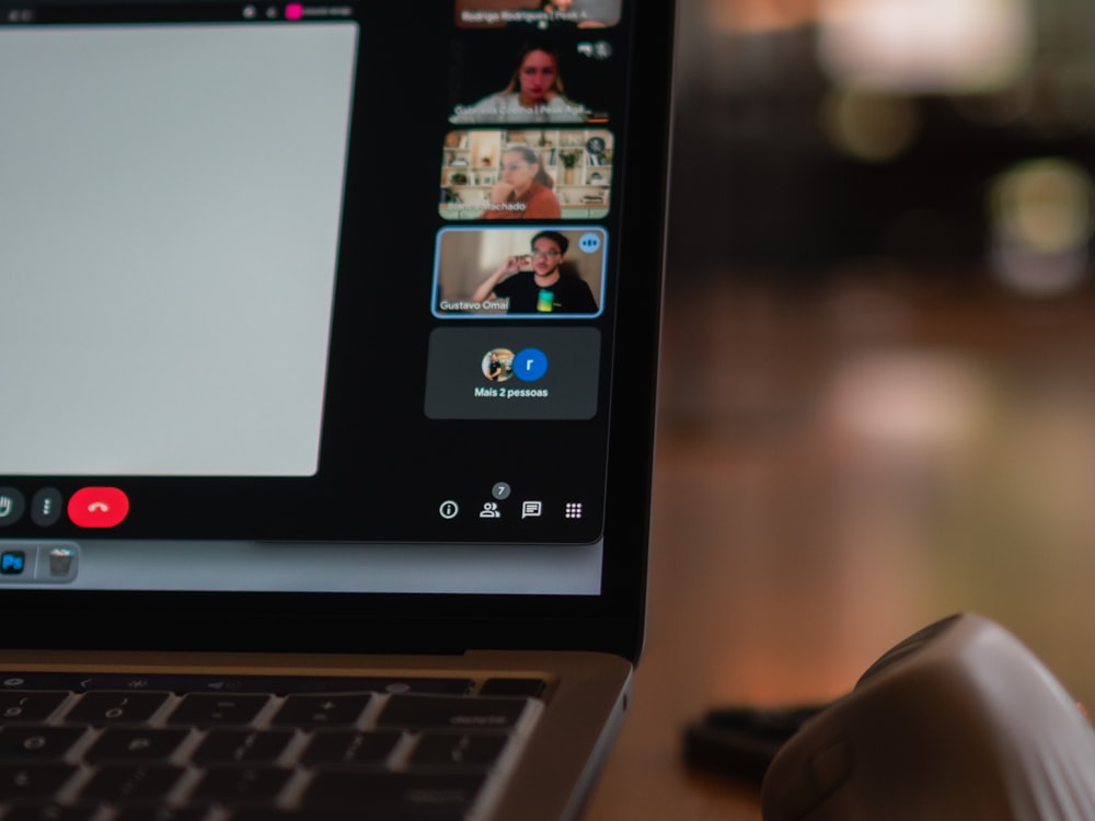 A laptop screen showing a video call with colleagues in different locations